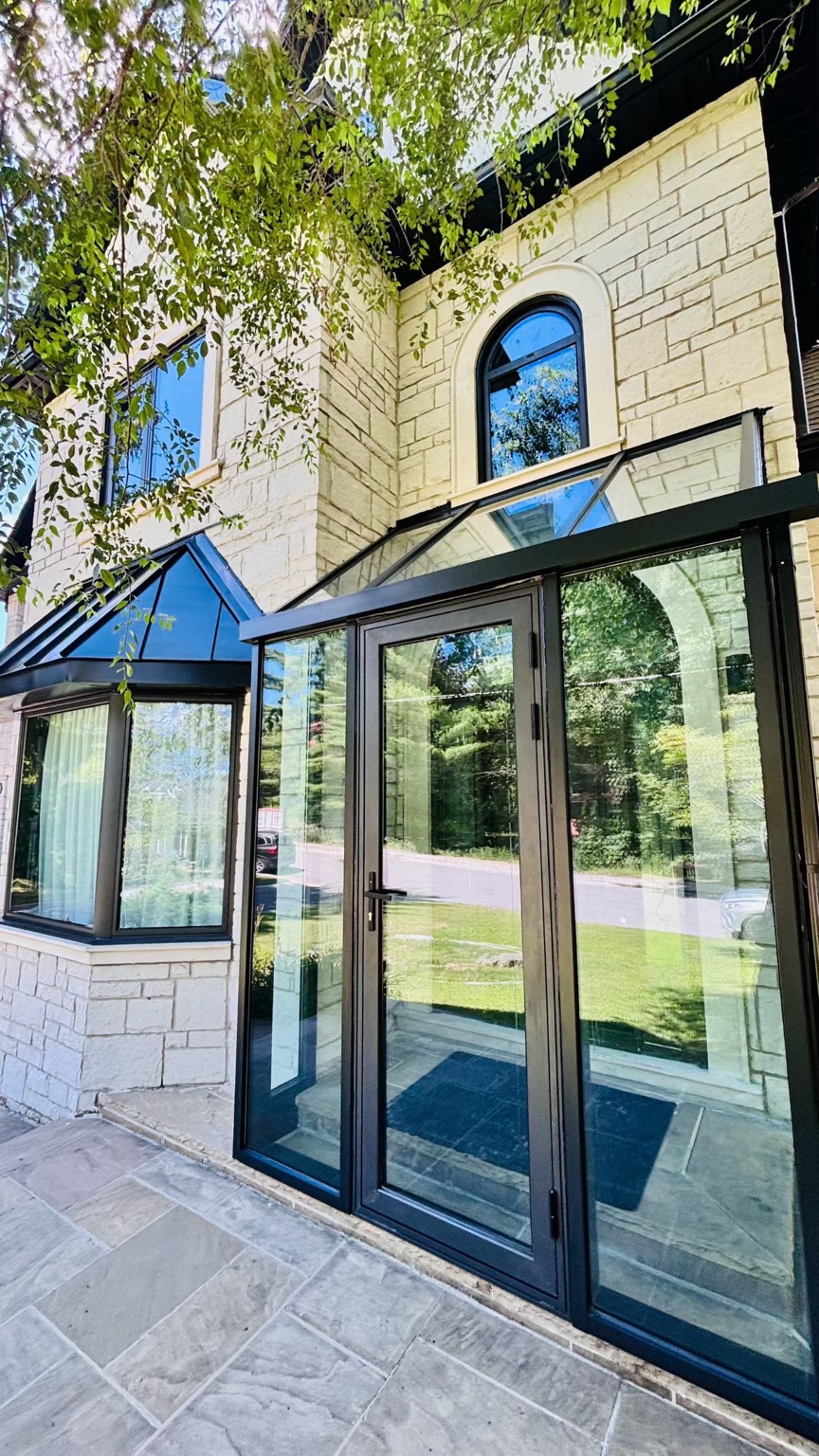 A glazed entrance enclosure beside a stone facade.